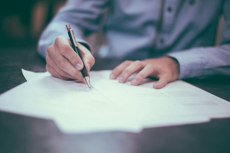 Man signs a document with a pen